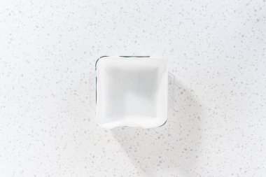 Flat lay. Lining glass baking pan with parchment paper sheet to prepare white chocolate cranberry pecan fudge.