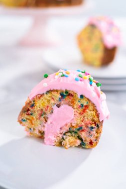 Manzarayı kapat. Dilimlenmiş funfettti demetli kek, üstünde pembe krema ve içinde krema var..