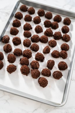 Naneli beyaz çikolatalı kurabiyeler pişirmek için parşömen kağıdıyla kaplı küçük bir hamur kepçesiyle kurabiye hamuru pişirmek..