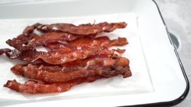 Adım adım. Beyaz tepside pişmiş pastırma şeritleri ve kağıt havlu..