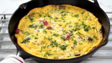 Zaman aşımı. Fırından yeni çıkmış ıspanak ve jambonlu frittata dilimliyorum..