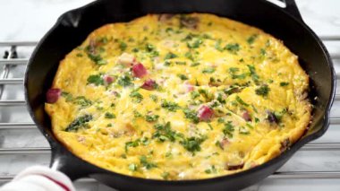 Fırından yeni çıkmış ıspanak ve jambonlu frittata dilimliyorum..