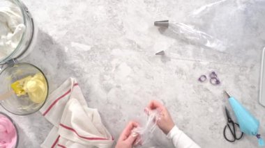 Düz yatıyordu. Adım adım. Tek boynuzlu at meringue kurabiyesi pişirmek için metal uçlu boru torbalarına krema karıştırılıyor..