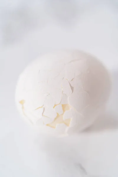 大理石のキッチンカウンターでゆで卵の皮をむく — ストック写真