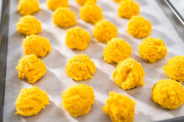 Beyaz çikolatalı limonlu kurabiye. Beyaz çikolatalı limonlu kurabiye pişirmek için parşömen kağıdıyla kaplı bir yemek tepsisine hamur kepçesiyle kurabiye pişirmek..