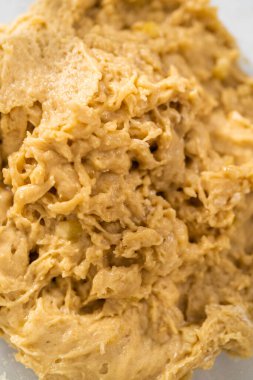 Mixing ingredients with a hand whisk in a large mixing bowl to bake banana cookies with chocolate drizzle.