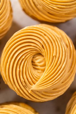 Karamelli vanilyalı keklerin üzerine tereyağlı krema dökerek..