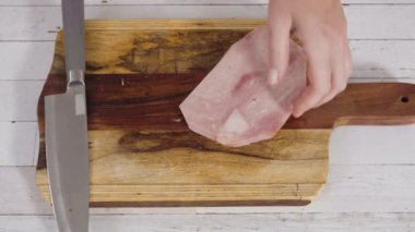 Ağaç kesme tahtasıyla organik ballı jambon kesmek.