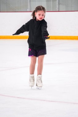 Küçük kız buz pateni pistinde artistik buz pateni yarışmasından önce pratik yapıyor..