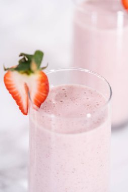 Taze taze çilek ve kağıt kamışla süslenmiş sağlıklı bir kahvaltı muzlu smoothie..