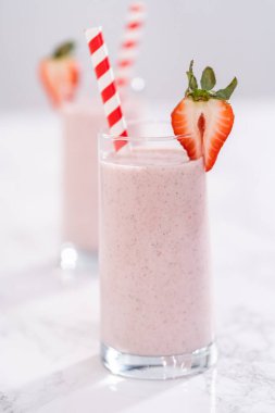Taze taze çilek ve kağıt kamışla süslenmiş sağlıklı bir kahvaltı muzlu smoothie..