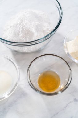 Measured ingredients in glass mixing bowls to make cream cheese glaze.