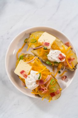 Fırında pişmiş patates. Tereyağı, ekşi krema, peynir ve pastırma parçalarıyla süslenmiş büyük fırında patates..