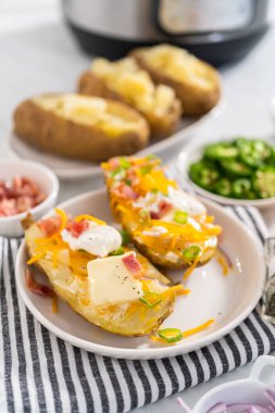 Fırında pişmiş patates. Tereyağı, ekşi krema, peynir ve pastırma parçalarıyla süslenmiş büyük fırında patates..