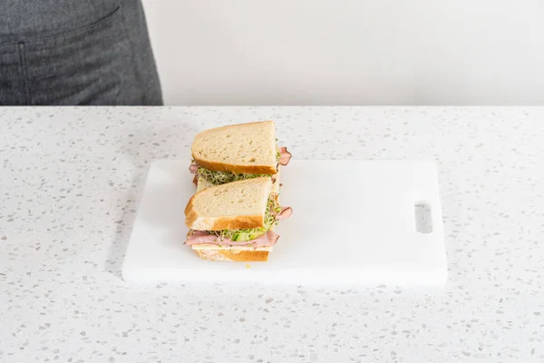 Assembling Ham Cucumber Sprout Sandwiches White Cutting Board — Stockfoto