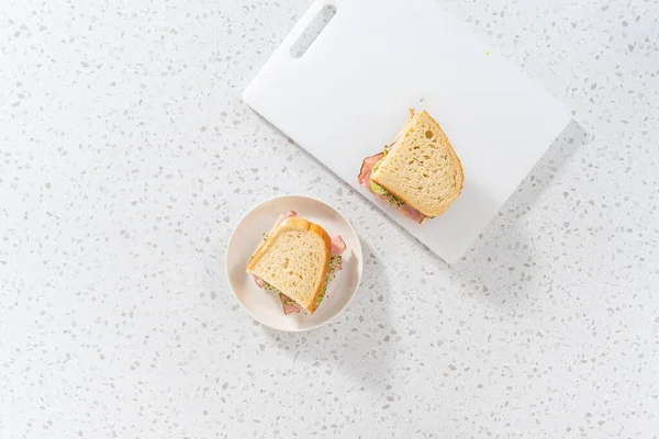 平置きだ 白いまな板の上にハムとキュウリともやしのサンドイッチ — ストック写真