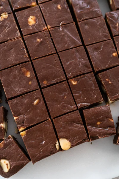 Büyük Bir Mutfak Bıçağıyla Çikolatalı Macadamia Şekerlemesini Beyaz Bir Kesme — Stok fotoğraf