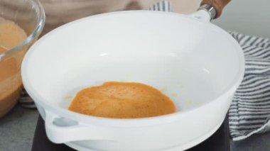 Time lapse. Step by step. Frying pumpkin pancakes batter on a white frying pan.