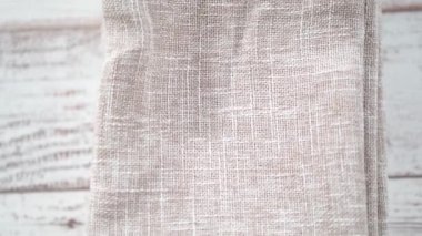 Yeni keten yemek peçetesini beyaz ahşap bir masada katlıyorum..