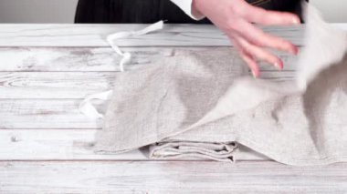 Yeni keten yemek peçetesini beyaz ahşap bir masada katlıyorum..