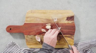 Ağaç kesme tahtasıyla organik sarımsak kesmek.