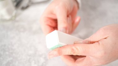 Kadın manikürünü evde basit manikür aletleriyle bitiriyor. Çivi tampon bloğu ile tampon çiviler.