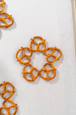 Dipping pretzels twists into melted chocolate to make a chocolate pretzel Christmas wreath.