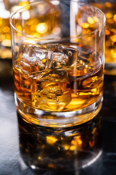 stock image Scotch on the rocks in whiskey glass on a black marble surface.