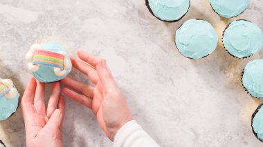 Düz yatıyordu. Adım adım. Çikolatalı kekleri tereyağlı krema ve gökkuşağı şekeriyle süslüyorum..