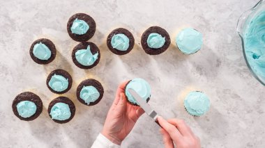 Düz yatıyordu. Adım adım. Çikolatalı keklerin üstüne mavi tereyağlı krema sürüyorum..