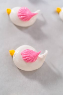 Paskalya kremalı kurabiye pişirmek için parşömen kağıdıyla kaplı pipo poşetleriyle merengi borulamak..