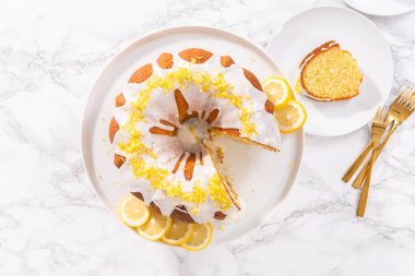 Düz yatıyordu. Pasta tezgahında limon aromalı dilimlenmiş limonlu kek..