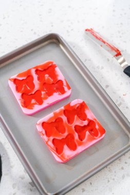 Flat lay. Filling bow silicone chocolate mold with melted chocolate to make a chocolate pretzel Christmas wreath.