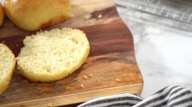 Adım adım. Odun kesme tahtasının üzerinde taze pişmiş çörekleri dilimliyorum..