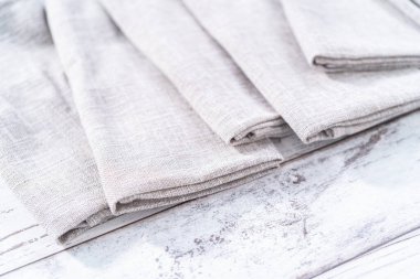 Ahşap beyaz bir masada doğal renkte keten bir peçetenin yakın görüntüsü..