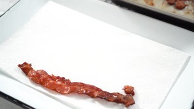 Adım adım. Beyaz tepside pişmiş pastırma şeritleri ve kağıt havlu..