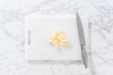 Düz yatıyordu. Beyaz bir kesme tahtasının üzerinde tuzsuz tereyağı dilimlemek.