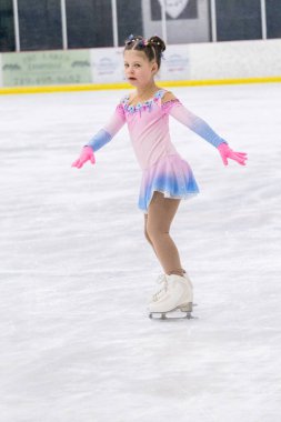 Küçük kız buz pateni pistinde artistik patinaj yapıyor..