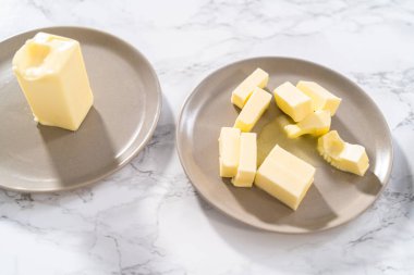 Tezgahın üzerinde yumuşatılmış tuzsuz tereyağı çubukları..