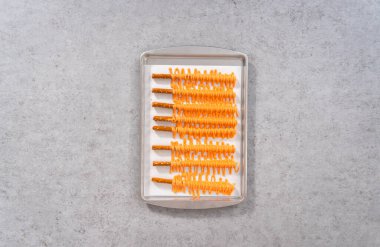 Düz yatıyordu. Çukulatalı çubuk çubuklara batırılmış parşömen kağıdıyla birlikte..