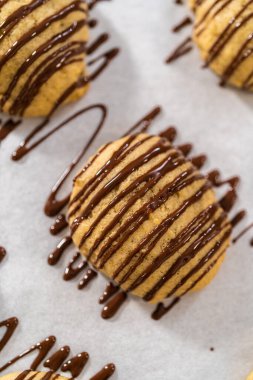 Muzlu kurabiyelerin üzerine erimiş çikolata serpiştirmek.