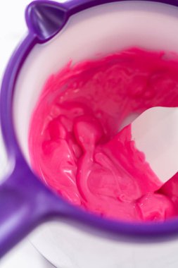 Çikolata kaplı çilek hazırlamak için çikolata parçalarını eritmek..