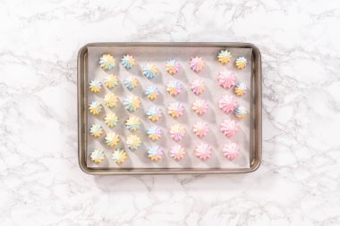 Düz yatıyordu. Fırınlanmamış unicorn meringue kurabiyeleri bir kağıt parşömen üzerinde.