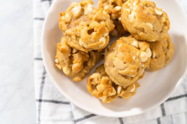Beyaz bir tabakta taze pişmiş beyaz çikolatalı macadamia fındığı..