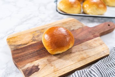 Odun kesme tahtasının üzerinde taze pişmiş çörekleri dilimliyorum..