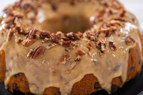 stock image Freshly baked chocolate pumpkin bundt cake with toffee glaze topped with toasted pecans.