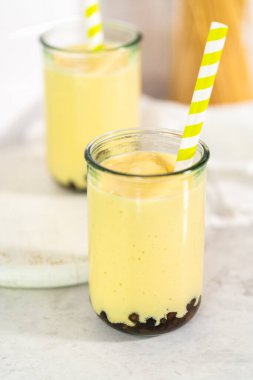 Taze yapılmış mango boba smoothie. Kağıt kamışla içme bardağında..