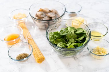 Sarımsaklı karides makarnasını ıspanakla hazırlamak için cam karışımında ölçülmüş malzemeler..