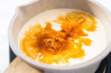 Beyaz çikolatalı ganache kreması yapmak için tencerede krem şanti ısıtılıyor..