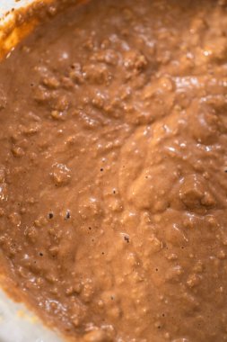 Büyük bir bardakta ıslak malzemeler karıştırarak kırmızı kadife kekler ve beyaz çikolatalı ganache kreması pişiriyorum..